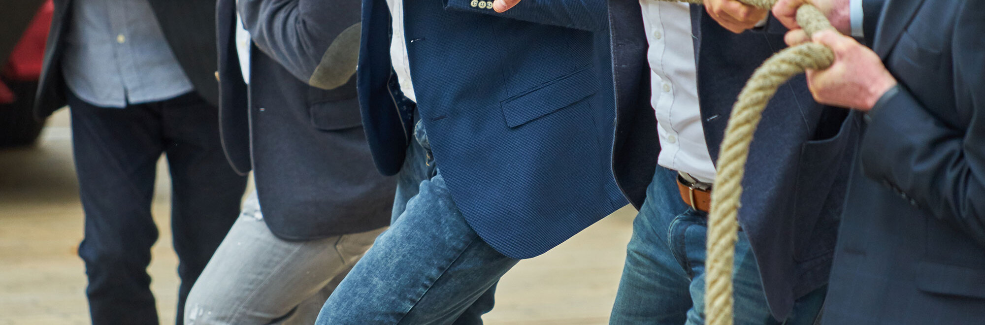 Eine Gruppe von Menschen in formeller Kleidung zieht an einem Seil bei einem Tauziehwettbewerb.